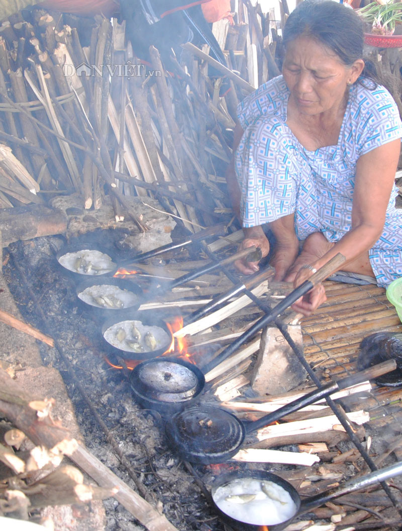 Phụ nữ đổ bánh cá kình bên cạnh đầm chuồn